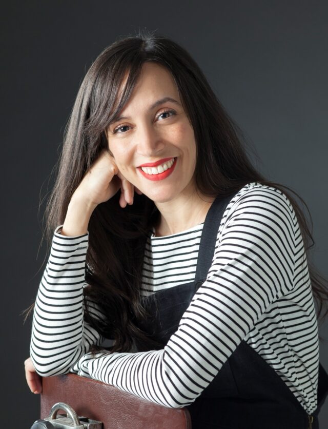 author photo: young woman with long dark hair in a striped shirt with one hand propped against her cheek