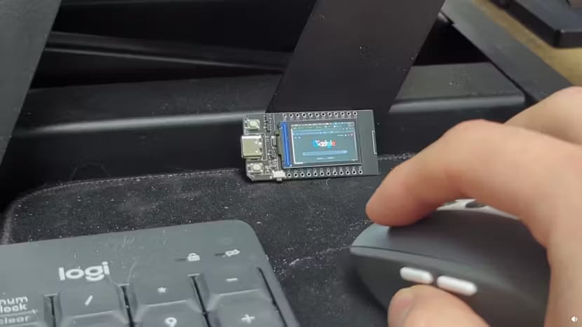 this picture shows a tiny desktop screen sat on a desk, with a keyboard, mouse, and hand visible